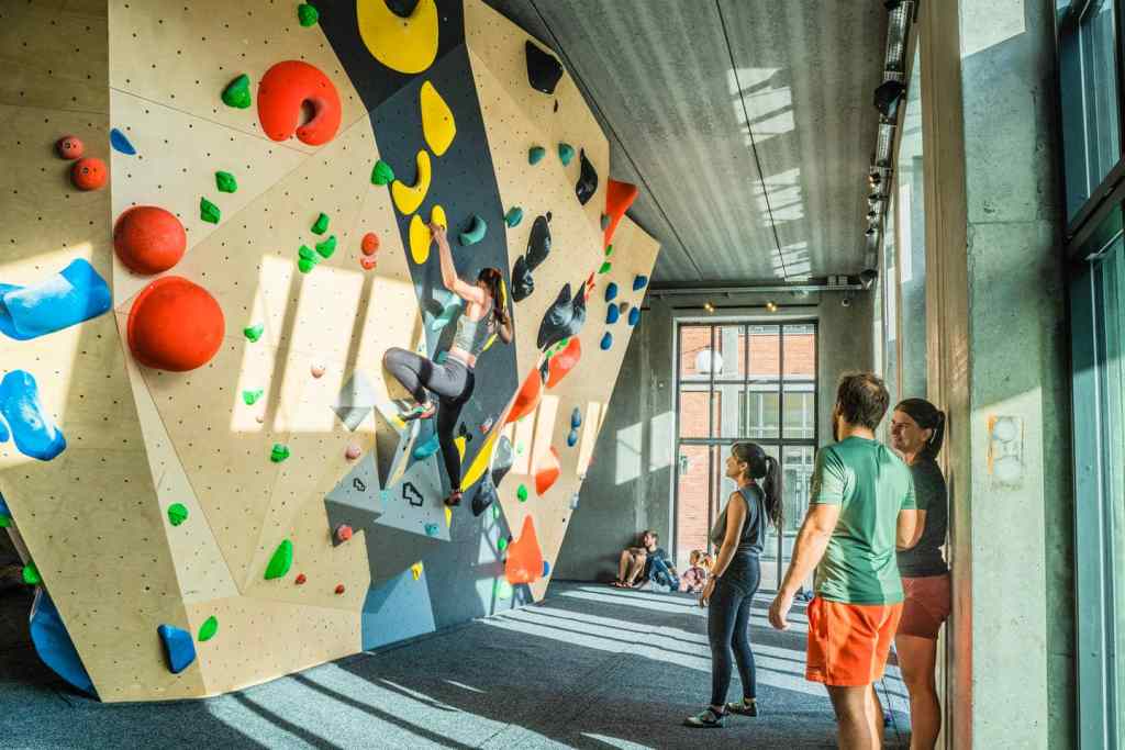 Climbers training in a bright, well ventilated indoor bouldering gym.